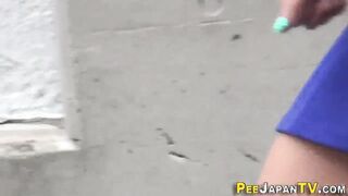 Asian pees behind car in public car park